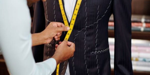 Profesional tailor making bespoke suit for client in his modern stidui